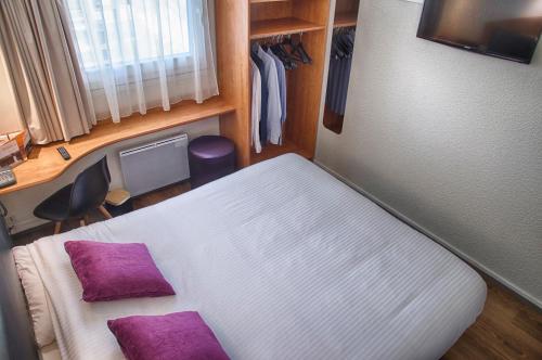 a small room with a bed with purple pillows at Logis Le Relais de Sassenage in Sassenage