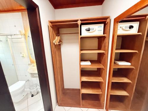 a bathroom with a closet with wooden shelves at Hotel Pousada da Lagoa - Casa Californiana in Garopaba