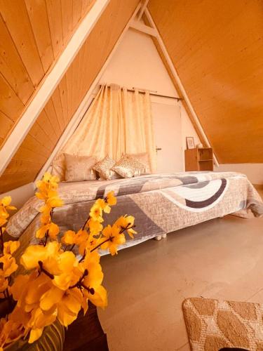 a bedroom with a bed and flowers in a attic at Frogs Aviator's Cottage in Dharmsāla