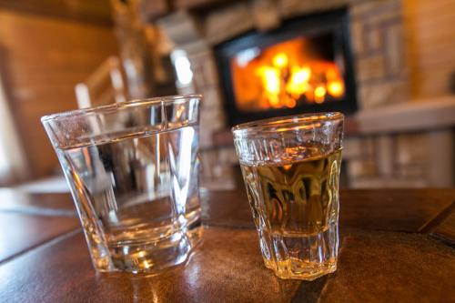 two glasses of water sitting on a table with a fireplace at Vila Dizdarevic Kopaonik in Kopaonik