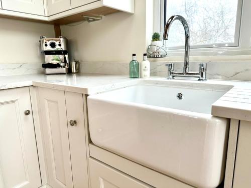 a white kitchen with a sink and a window at Holly Barn in Worcester