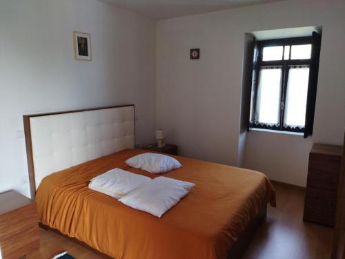 a bedroom with a bed with two pillows and a window at Quinta da Preciosa in Nebrijo