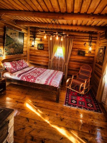 a bedroom in a log cabin with a bed and a chair at Еко Садиба Під Полониною in Sasivka