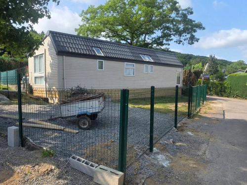 a house with a fence and a trailer in front of it at La cabane des fées in Yvoir