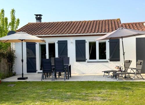 a patio with two umbrellas and a table and chairs at Dune Nest 233 - beautiful house near beach - up to 4 guests with garden, parking, WLAN in Bredene
