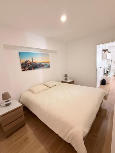 a white bedroom with a white bed and a picture on the wall at Namaste in Sesimbra