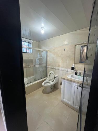 a bathroom with a toilet and a tub and a sink at Gladi Hidalgo in San Francisco de Macorís
