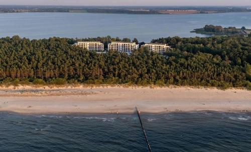 an island in the water with a resort on a beach at Essentia Apartament 405 in Dziwnów