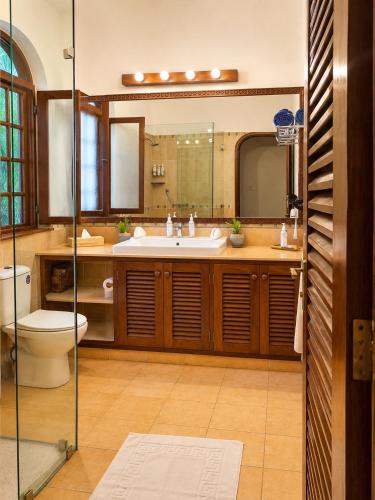 a bathroom with a sink and a toilet and a mirror at Asha Boutique Hotel in Diani Beach