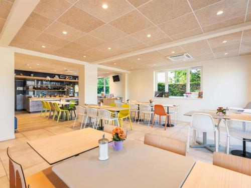 a restaurant with tables and chairs and a cafeteria at Ibis Budget Sélestat in Sélestat