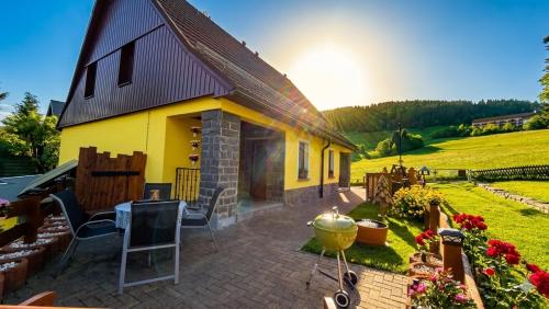 a small yellow house with a patio and a yard at Ferienwohnung-direkt-am-Skihang mit Sauna in Kurort Oberwiesenthal