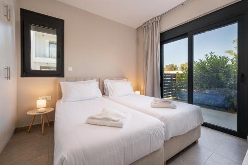 a bedroom with two beds and a large window at Luxe benedenwoning Nula Kos in Kos