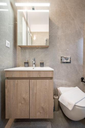 a bathroom with a sink and a toilet and a mirror at Luxe benedenwoning Nula Kos in Kos