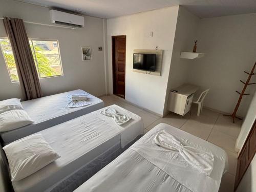 ein Schlafzimmer mit zwei Betten und einem Fernseher in der Unterkunft Hotel Ondas do Mar in Salinópolis