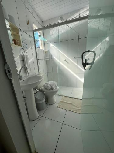 a bathroom with a toilet and a glass shower at Pousada Caminho das Aguas in Lindóia