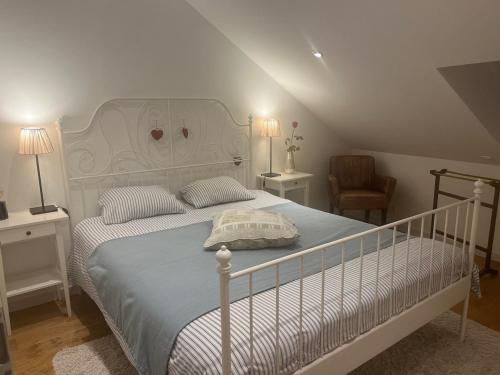 ein Schlafzimmer mit einem weißen Bett und einem Stuhl in der Unterkunft Chez Arli in Attert