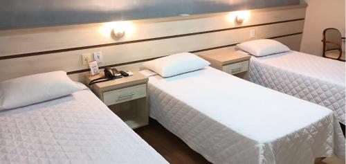 a hotel room with two beds and a desk at Hotel Premier in Santa Rita