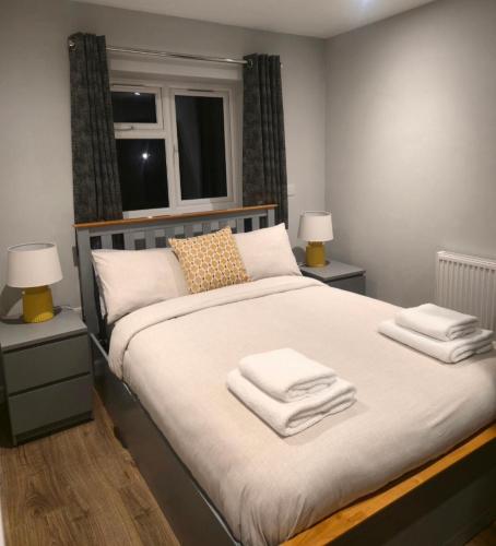 a bedroom with a large bed with towels on it at Yew Tree Retreat- Sunset Suite in Newbury