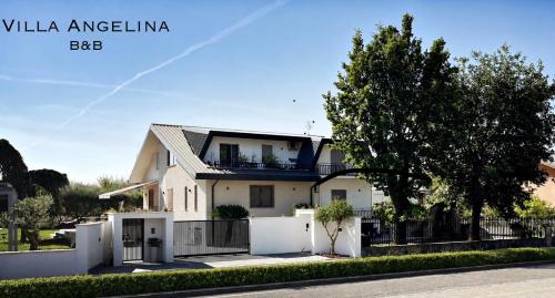 a white house with a fence and a tree at Villa Angelina in Aquino