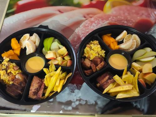 two black containers filled with different types of food at Hotel Riviera del Atrato in Bojayá