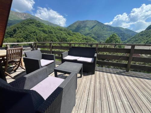 a deck with chairs and tables with mountains in the background at Chalet Vue Montagne 6 personnes proche Sanctuaire de La Salette in La Salette-Fallavaux