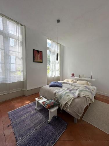 a bedroom with a large bed and a blue rug at Orphé37, grand appartement cocon au cœur de la Gascogne artistique in Lectoure