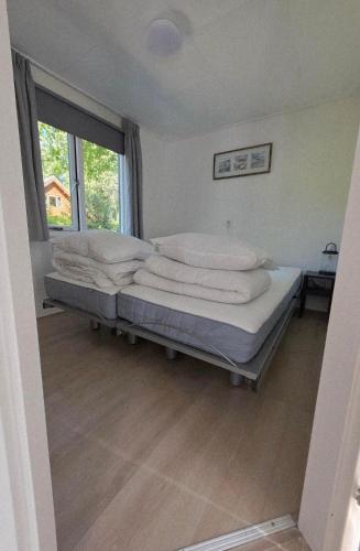 a bedroom with a bed with white pillows and a window at Robin's oak lodge in Epe
