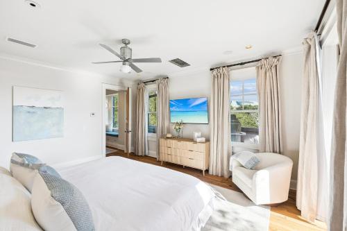 a white bedroom with a bed and a chair at Serenity Now in Rosemary Beach