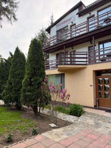 a building with a tree and flowers in front of it at Pensiunea Crescent Predeal in Predeal