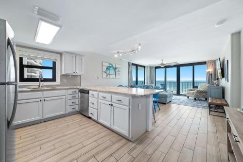 a kitchen with white cabinets and a living room with a table at Lei Lani Unit 201T in Orange Beach