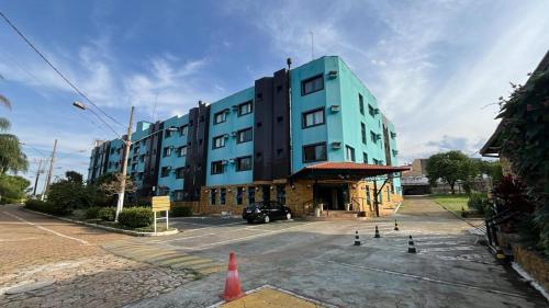 a blue building with a car parked in a parking lot at Hotel Maracanã in Pouso Alegre