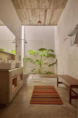 a bathroom with a sink and a toilet and a bench at Casa Carmen Morelos in Oaxaca City