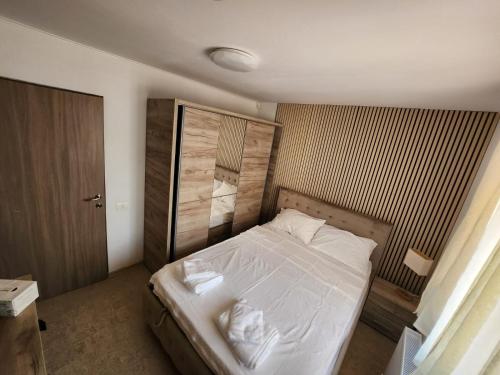 ein Schlafzimmer mit einem weißen Bett mit hölzernem Kopfteil in der Unterkunft CasaMari in Corbu