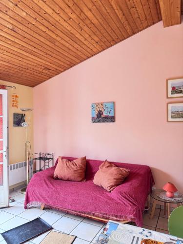 a purple couch in a room with a wooden ceiling at La petite Lotie in Saint-Denis-dʼOléron