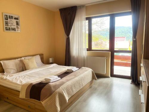 a bedroom with a bed and a large window at Chic Peak Apartment - Kalinderu Slope & View in Buşteni