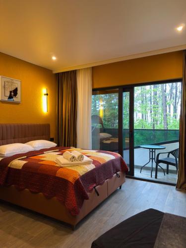 a bedroom with a bed and a balcony with a table at Bellissimo Aparthotel Aqua in Shekhvetili