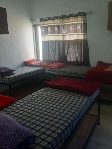 a room with three beds and a window at Paarijat PG in Udaipur