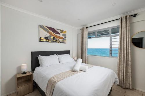a bedroom with a bed and a window with the ocean at Rustic Beachfront Apt! Shared Pool! in Umdloti
