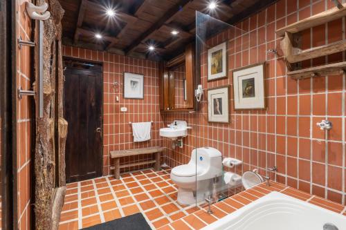 an orange tiled bathroom with a toilet and a sink at Finca Campestre La Adelita B&B in Salento