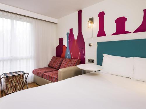 a bedroom with a bed and a couch at ibis Styles Barnsley in Barnsley