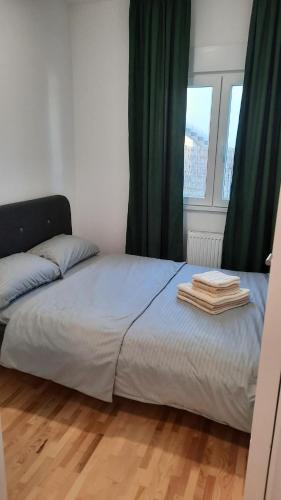 a bed in a bedroom with green curtains at Apartman Sanja Ledine in Ledine