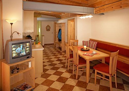 a living room with a television and a table and chairs at Apart Ehart in Sankt Anton am Arlberg