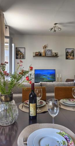 a table with a bottle of wine and glasses on it at Apartman Mara in Risan
