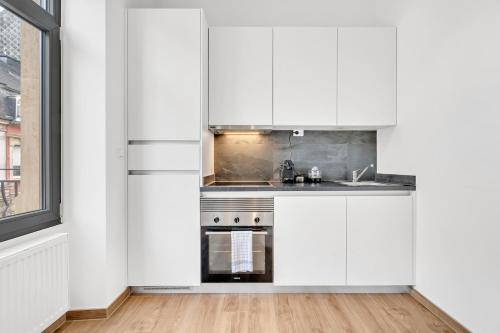 a kitchen with white cabinets and a window at Résidence Welter Luxembourg in Luxembourg