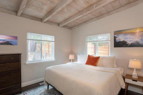 a white bedroom with a bed and two windows at 3890 Cypress Rest in Pebble Beach