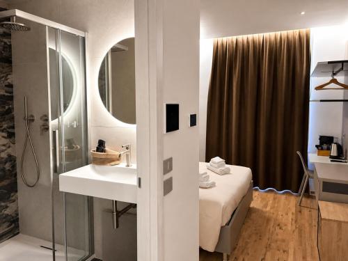 a bathroom with a sink and a bed and a mirror at Luxury Lodge - Moderno Residence vicino alla Stazione in Trieste