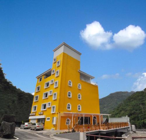 un edificio amarillo con coches estacionados frente a él en Cheng-Ping Hot Spring Inn, en Wenquan