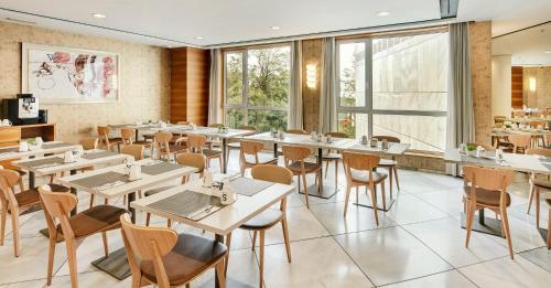 a restaurant with white tables and chairs and windows at Sercotel Sorolla Palace in Valencia
