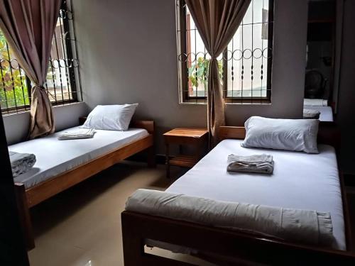 two beds in a room with two windows at Moshi Green Lodge in Moshi