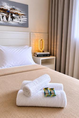 a bed with two towels and a mirror on it at MaxLoft - Studio Moderno in Joinville